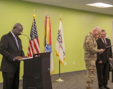 Kyle Tucker (left), Assistant Project Manager of Cyber Maneuver, narrated the ceremony as COL Chad Harris (center) presented the Applied Cyber Technologies charter to Joe Kobsar (right).