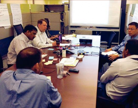 Five men sit around conference table.