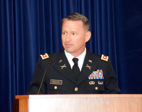 Soldier in dress uniform speaks at podium.