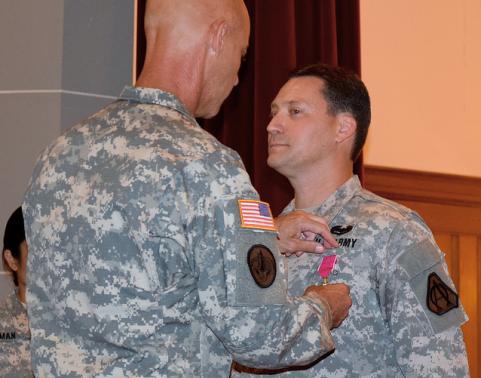 Soldier pins medal onto another soldier.