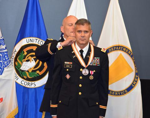 Soldiers places medal around the neck of another soldier.