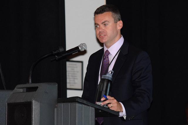 Man speaks into microphone at podium.