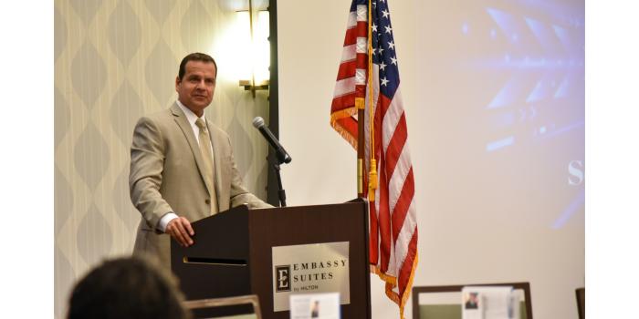 Man at podium with U.S. flag