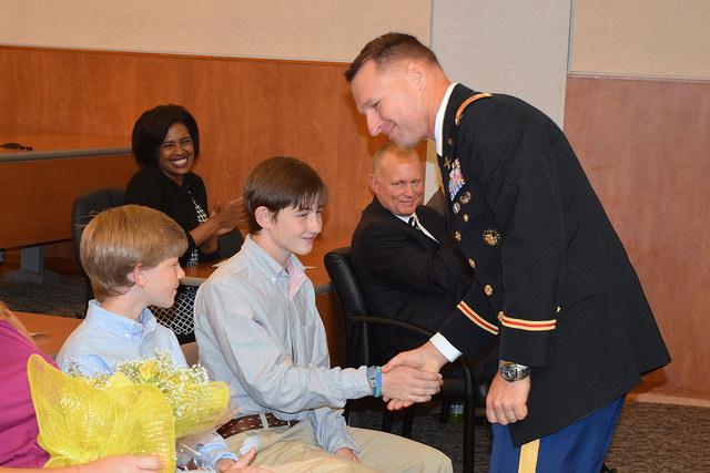 Soldier shakes a teenage boy's hand.