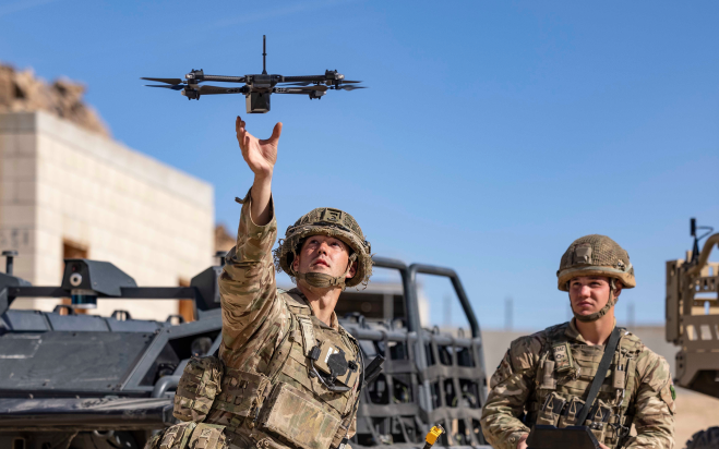 An image of men in military uniforms flying a drone.
